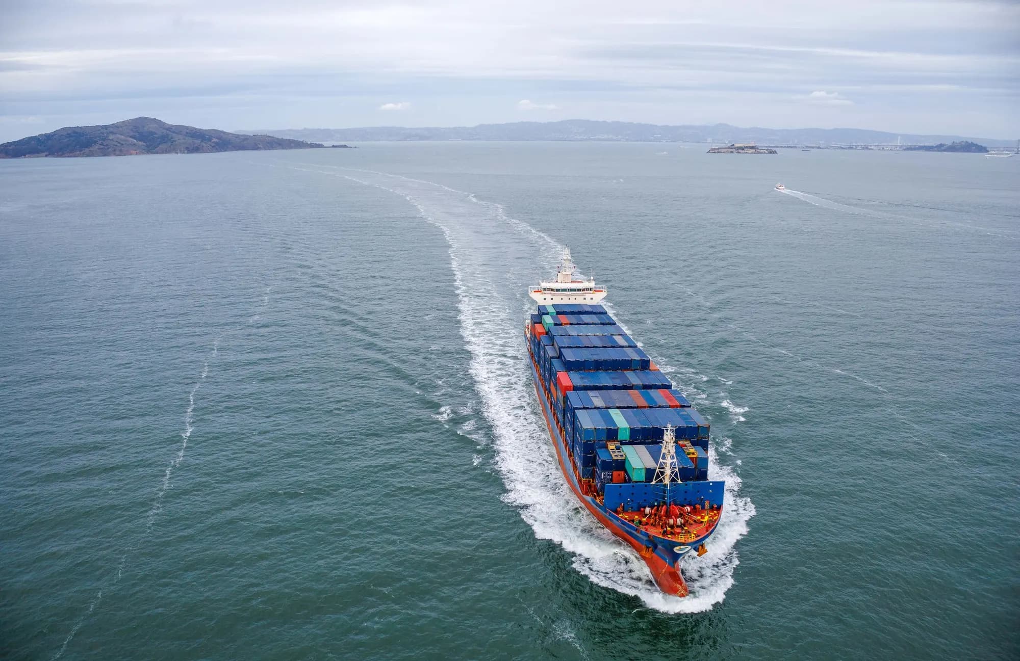 A loaded container ship underway at sea, seen from above